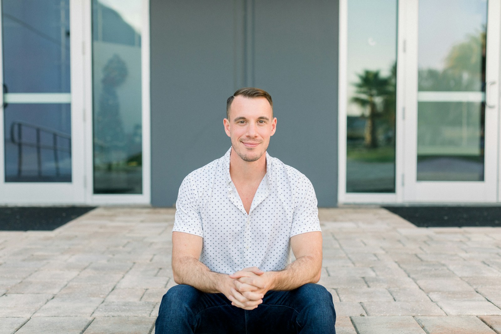 a man sitting on the ground in front of a building